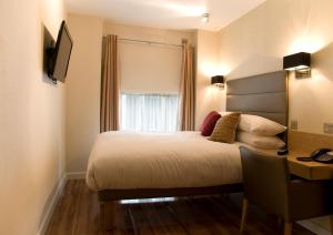 a bedroom with a bed and a desk and a window at The Jade in London