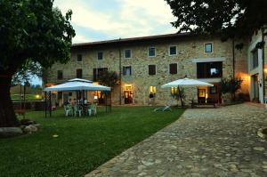 un bâtiment avec des tables et des parasols devant lui dans l'établissement Agriturismo Borgo Floreani, à Vendoglio