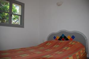 a bed with a colorful comforter and a window at Residence Ribellinu in Pianottoli-Caldarello