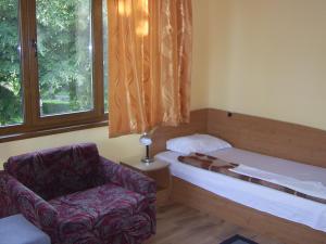 a room with a bed and a chair and a window at Nelly Guest House in Sozopol