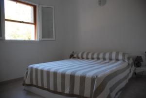 a bed in a white room with a striped blanket at Residence Ribellinu in Pianottoli-Caldarello