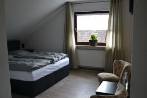 a bedroom with a bed and a window and a chair at Pension Zum Wilhelm in Germerode