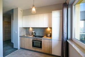 a kitchen with white cabinets and a sink and a window at Apartamenty City View od WroclawApartament-pl in Wrocław