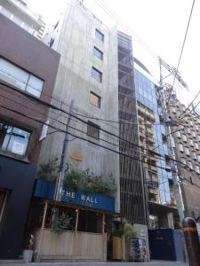a tall building with a sign that reads the wall at The Wall Hotel in Osaka