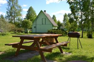 a picnic table with a grill and a bench in a field at Paju Holiday Home in Otepää