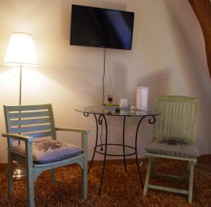 two chairs and a table with a tv on a wall at Domaine De Potofayol in Lacropte