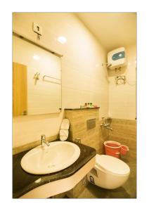 uma casa de banho com um lavatório, um WC e um espelho. em Hotel Ashoka em Rameswaram