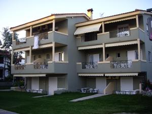 un gran edificio de apartamentos con césped delante en By the Sea Apartments-studios, en Siviri