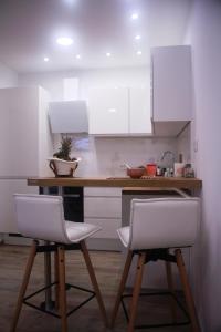 a kitchen with white cabinets and two white chairs at M-Dream, in heart of Split in Split