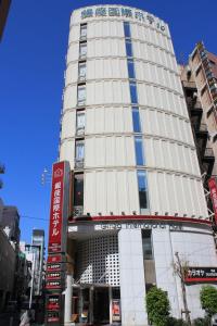 Un grand bâtiment blanc avec un panneau devant. dans l'établissement Ginza International Hotel, à Tokyo