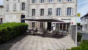 a table with chairs and an umbrella in front of a building at Saveurs De l'Abbaye in Saintes