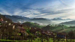 un pueblo en una colina con niebla en las montañas en Aptos. Rurales Los Falares de la Abuela Berta (Adults Only), en Nieda