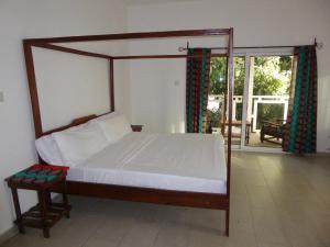 1 dormitorio con cama con dosel y patio en Sarawally Guesthouse, en Ampaya