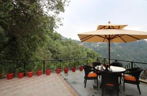 a patio with a table and an umbrella at The Oaktree House in Shimla
