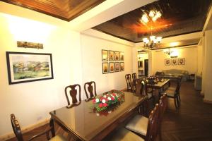 a dining room with two tables and chairs with flowers at The Oaktree House in Shimla