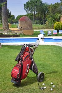 a golf bag sitting on the grass next to a pool at Hotel & Golf Ca La Caputxeta in Castelló d'Empúries