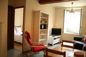 a living room with a red chair and a bedroom at Carcassonne Pont Vieux Apartments in Carcassonne