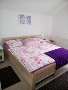a bedroom with a bed with a purple comforter at Rooms Marina in Korenica