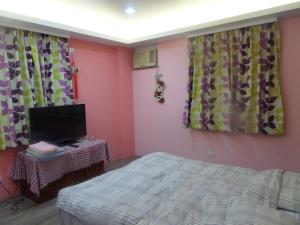 1 dormitorio con 1 cama, TV y cortinas en Lai Yi Ke B&B, en Dongshan