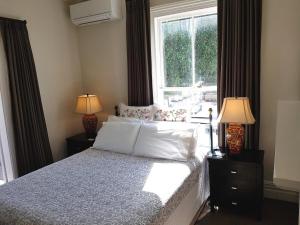 a bedroom with a bed with two lamps and a window at Ponsonby Manor in Auckland