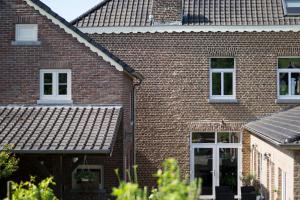 une maison en briques avec des fenêtres blanches et un toit dans l'établissement Huize Mesch, à Eijsden