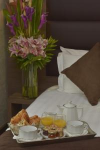 a tray of breakfast food on a bed with flowers at Unic Renoir Saint Germain in Paris