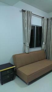 a brown couch in a room with a window at Muang Thong Home for Rent in Ban Bang Phang