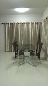 a glass table and chairs in a room with curtains at Muang Thong Home for Rent in Ban Bang Phang