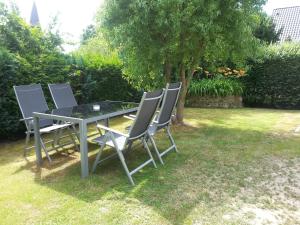 a glass table and chairs in a yard at Ferienwohnungen Vallentin GbR in Schaprode