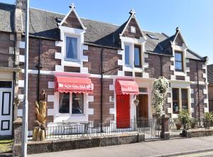 uma casa com uma porta vermelha numa rua em Acer Glen B&B em Inverness