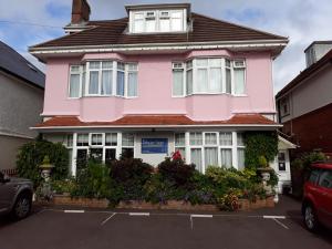 ein rosafarbenes Haus mit einem davor geparkt in der Unterkunft Shoreline Accommodation in Bournemouth