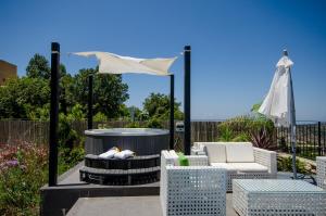 een patio met een hot tub, stoelen en een parasol bij The Fifties suites in Kefar Weradim