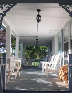 a porch with white rocking chairs and a chandelier at The Harbor Inn in Kennebunkport