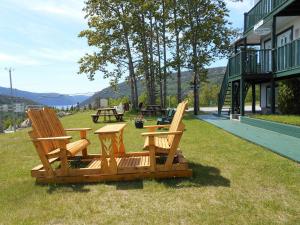two chairs and a picnic table in the grass at Hôtel Sous la Croix 152725 in Tadoussac