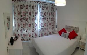 エル・メダノにあるMontaña Rojaのベッドルーム1室(白いベッド1台、赤い枕、窓付)