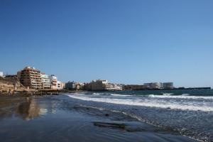 uma praia com o oceano e edifícios ao fundo em Montaña Roja em El Médano