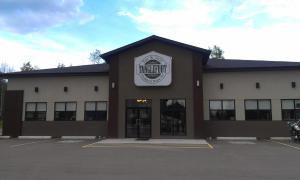 a building with a sign on the front of it at Sigma Inn & Suites Hudson's Hope in Hudson Hope