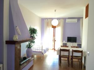 un soggiorno con tavolo, sedie e TV di Apartment Arianna 150mt from beach a Castelsardo