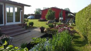 MahlzowにあるFerienhaus Storchenwegの木製デッキと赤い家がある庭園