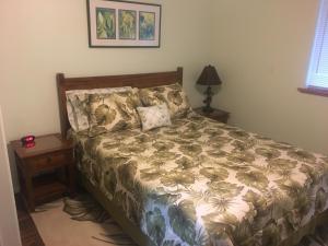 Aloha Big Island Paradise في Mountain View: غرفة نوم بسرير وموقف ليلي مع مصباح