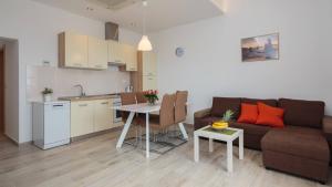 a living room with a couch and a table and a kitchen at Apartmani Ujakovic in Kaštela