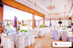 a banquet hall with white tables and white chairs at Nanjing Restaurant & Motel in Kampala