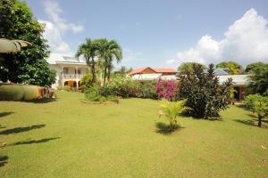 a yard with a house in the background at Au Domaine Des Bougainvilliers in Sainte-Rose