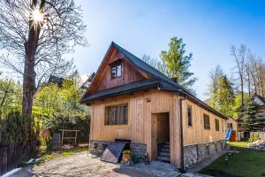a large wooden house with a dog sitting in front of it at Domek Potocek in Zakopane