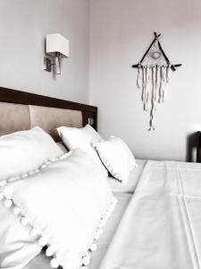 1 cama con almohadas blancas y reloj colgando en la pared en Calypso Beach Hotel, en Loutra Edipsou