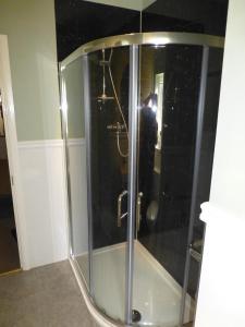 a shower with a glass door with a person taking a picture at The Dales in Stanhope