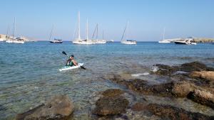a person in a kayak in the water with boats at Vrahos Boutique Hotel in Karavostasi