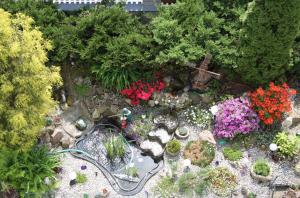 a miniature garden with flowers and a pond at Villa Anastazis - Penzion Eden in Karlovy Vary