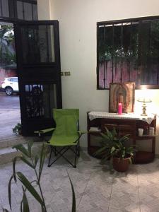 Habitación con silla verde, mesa y escritorio. en Hotel Florida, en Villahermosa
