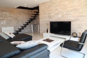 a living room with a black leather couch and a tv at Villa Sunshine in Trogir